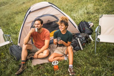 Birbirine aşık çiftler çimenlerde oturur, kampın tadını çıkarır, sohbet ederler.