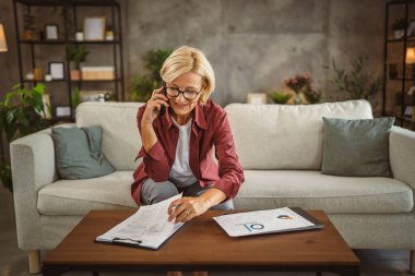 Olgun bir son sınıf öğrencisi panoda çalışıyor ve cep telefonuyla konuşuyor.