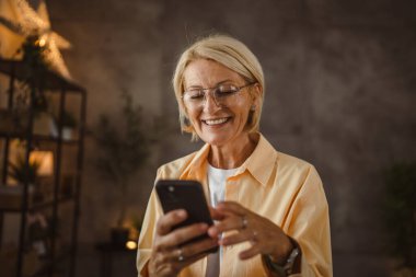 Olgun yaşlı kadın cep telefonundan satın alır ve kredi kartı kullanır.