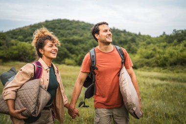 Erkek arkadaş ve kız arkadaş kamp malzemeleriyle ormanda dolaşıyorlar.