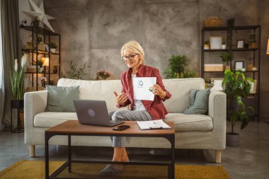 Evde çalışan olgun yaşlı bir kadın video aracılığıyla danışmanlık yapıyor.