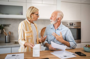 Ciddi sinirli yaşlı çift, iç hesapları ödemek için faturaları hesaplıyor.