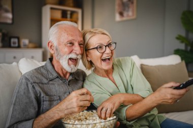 Yaşlı karı koca kanepede oturur, film izler ve patlamış mısır yerler.