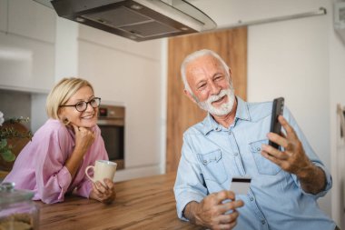 Üst düzey karı koca mutfaktaki cep telefonundan online Whit kredi kartı alıyorlar.