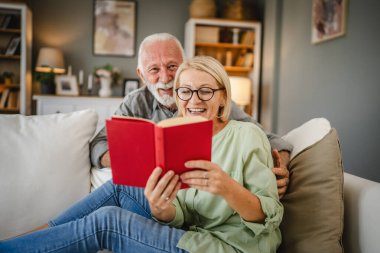 Olgun bir eş kanepeye uzanır kitap okur ve kıdemli kocasıyla bu konuyu tartışır.