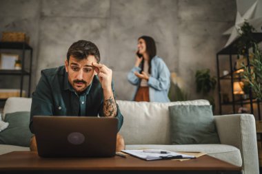 Yetişkin beyaz adam evde çalışıyor ve laptop ve kağıtları kullanıyor.