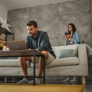 Yetişkin beyaz adam evde çalışıyor ve laptop ve kağıtları kullanıyor.