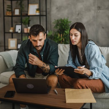 Yetişkin beyaz çift kız arkadaşı ve erkek arkadaşı evde çalışıyor ve laptop kullanıyorlar.