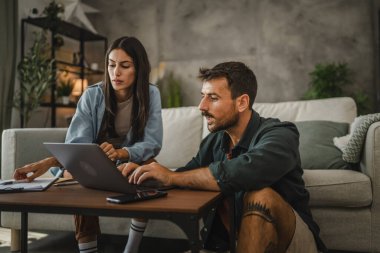 Yetişkin beyaz çift kız arkadaşı ve erkek arkadaşı evde çalışıyor ve laptop kullanıyorlar.