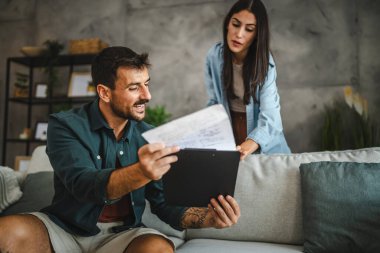 Kız arkadaşı ona cep telefonu ekranını gösterirken erkek arkadaşı panoyu tutuyor ve okuyor.