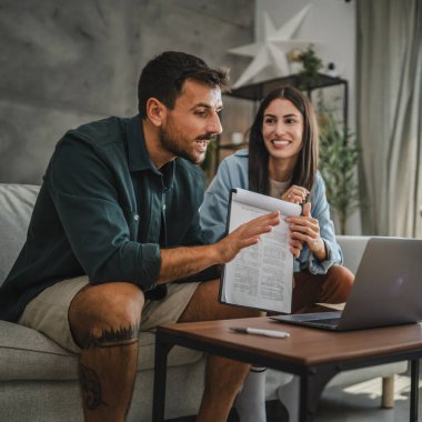 Çift evde dizüstü bilgisayarda çalışıyor ve video görüşmesi için hisse senedi sözleşmesi veya panoya sigorta yaptırıyor.