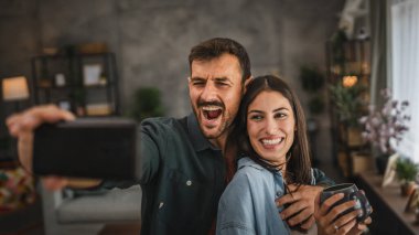 Erkek arkadaşı onun ve kız arkadaşının cep telefonuyla kendi portresini çekiyor.