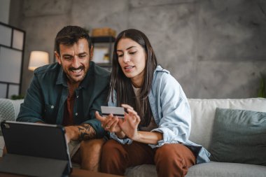 Yetişkin beyaz bir çift dijital tabletten kredi kartıyla online alışveriş yapıyor.