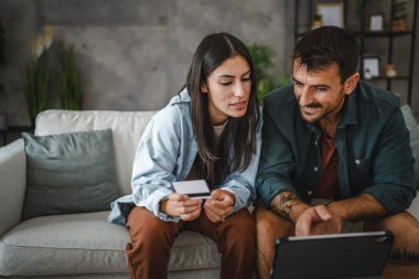 Yetişkin beyaz bir çift dijital tabletten kredi kartıyla online alışveriş yapıyor.