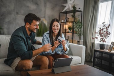 Yetişkin beyaz bir çift dijital tabletten kredi kartıyla online alışveriş yapıyor.