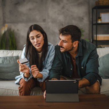 Yetişkin beyaz bir çift dijital tabletten kredi kartıyla online alışveriş yapıyor.