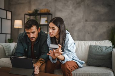 Yetişkin beyaz bir çift dijital tabletten kredi kartıyla online alışveriş yapıyor.