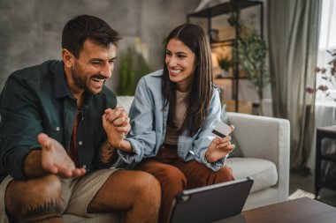 Yetişkin beyaz bir çift dijital tabletten kredi kartıyla online alışveriş yapıyor.