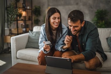 Yetişkin beyaz bir çift dijital tabletten kredi kartıyla online alışveriş yapıyor.