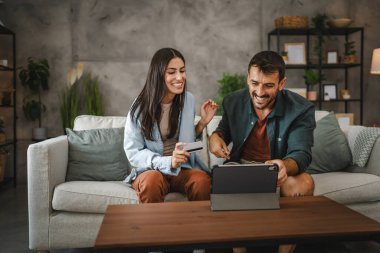 Yetişkin beyaz bir çift dijital tabletten kredi kartıyla online alışveriş yapıyor.