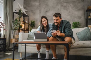 Yetişkin beyaz bir çift dijital tabletten kredi kartıyla online alışveriş yapıyor.