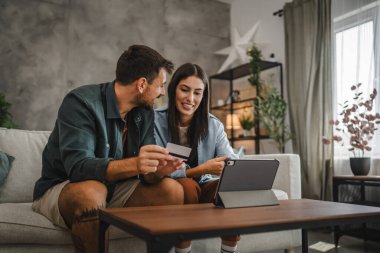 Yetişkin beyaz bir çift dijital tabletten kredi kartıyla online alışveriş yapıyor.