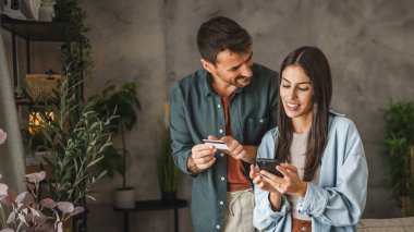 Yetişkin Kafkasyalı çift cep telefonlarını evde kredi kartıyla satın alıyor.