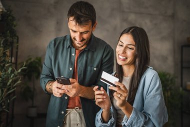 Yetişkin Kafkasyalı çift cep telefonlarını evde kredi kartıyla satın alıyor.