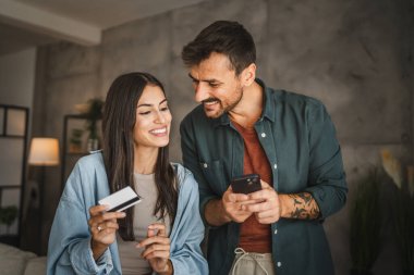 Yetişkin Kafkasyalı çift cep telefonlarını evde kredi kartıyla satın alıyor.