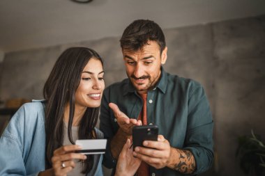 Yetişkin Kafkasyalı çift cep telefonlarını evde kredi kartıyla satın alıyor.
