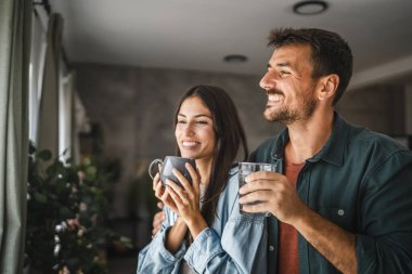 Çift portresi kahve ve suyla ayakta duruyor, pencereye bakın.