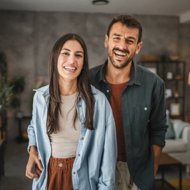 Güzel bir çiftin portresi ayakta durur, gülümser ve evde kucaklaşır.