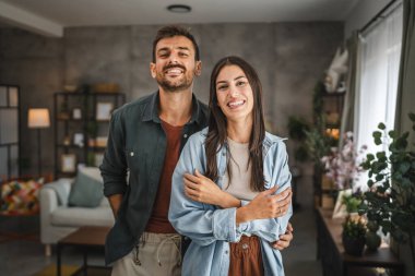 Güzel bir çiftin portresi ayakta durur, gülümser ve evde kucaklaşır.