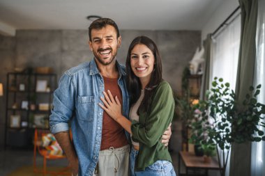 Güzel bir çiftin portresi ayakta durur, gülümser ve evde kucaklaşır.