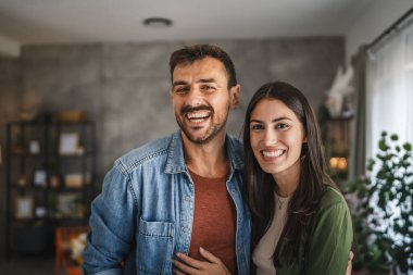 Güzel bir çiftin portresi ayakta durur, gülümser ve evde kucaklaşır.