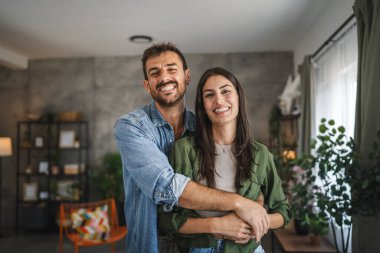 Güzel bir çiftin portresi ayakta durur, gülümser ve evde kucaklaşır.