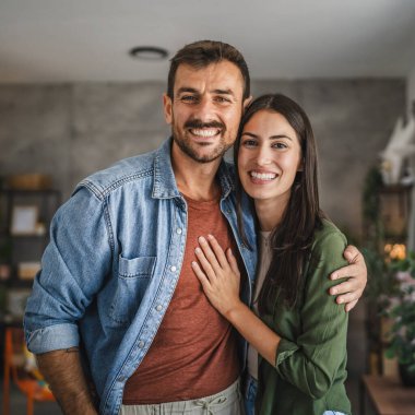 Güzel bir çiftin portresi ayakta durur, gülümser ve evde kucaklaşır.