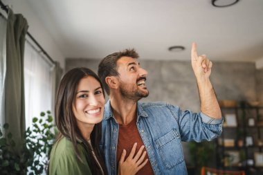 Güzel bir çiftin portresi ayakta durur, gülümser ve evde kucaklaşır.