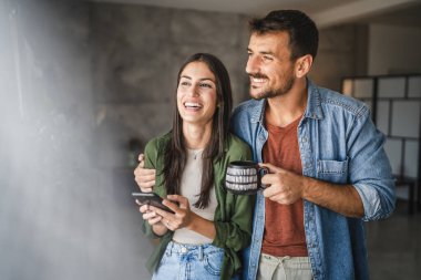 Bir fincan kahve ve cep telefonuyla duran çift portresi pencereyi tanıt.