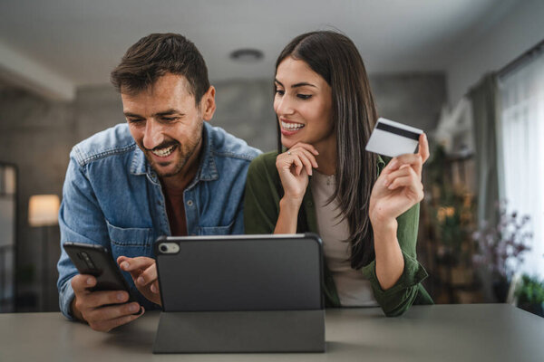 boyfriend buy online on mobile phone while girlfriend hold credit card