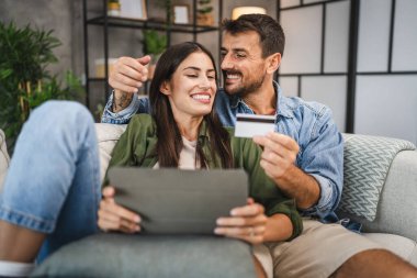 Yetişkin beyaz bir çift dijital tabletten kredi kartıyla online alışveriş yapıyor.