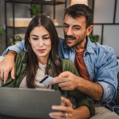 Yetişkin beyaz bir çift dijital tabletten kredi kartıyla online alışveriş yapıyor.