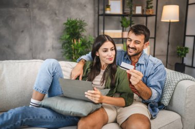 Yetişkin beyaz bir çift dijital tabletten kredi kartıyla online alışveriş yapıyor.