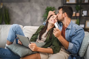 Yetişkin beyaz bir çift dijital tabletten kredi kartıyla online alışveriş yapıyor.
