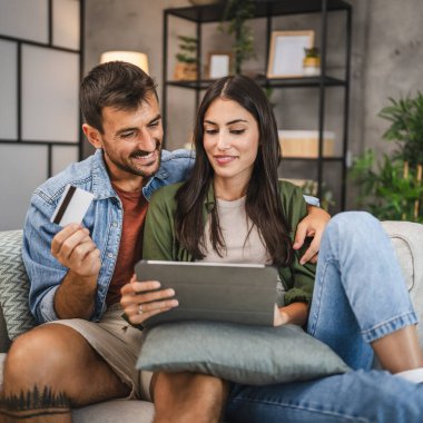 Yetişkin beyaz bir çift dijital tabletten kredi kartıyla online alışveriş yapıyor.