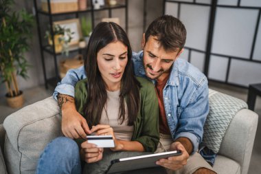 Yetişkin beyaz bir çift dijital tabletten kredi kartıyla online alışveriş yapıyor.