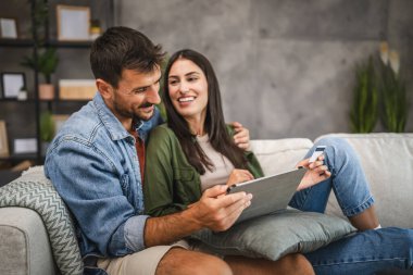 Yetişkin beyaz bir çift dijital tabletten kredi kartıyla online alışveriş yapıyor.