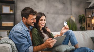 Yetişkin beyaz bir çift dijital tabletten kredi kartıyla online alışveriş yapıyor.