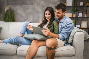 Yetişkin beyaz bir çift dijital tabletten kredi kartıyla online alışveriş yapıyor.