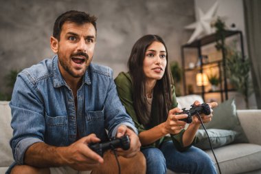 Yetişkin çiftler joystick 'te video oyunu oynarken eğleniyorlar.